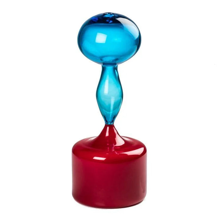 A modern glass sculpture or vase with a glossy red cylindrical base and a translucent blue bulbous top, centered on a plain white background.